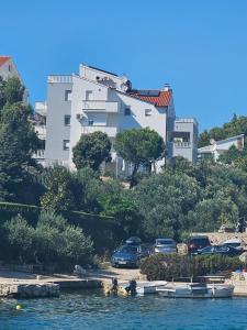 ein weißes Gebäude auf einem Hügel mit Booten im Wasser in der Unterkunft Apartments Ani in Zaboric
