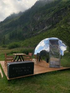 ein Zelt auf einer Holzterrasse mit einem Picknicktisch in der Unterkunft The Lynx in Salvan