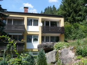 a yellow house with a balcony on a hill at Ferienwohnung Dittmar am Kaffeehof in Bad Liebenzell