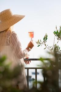 a woman in a straw hat holding a wine glass at Hotel California by Aycon in Sveti Stefan