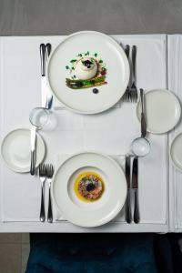a white table with two plates and silverware on it at Hotel California by Aycon in Sveti Stefan