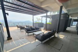 eine Terrasse mit Sofas und Tischen auf dem Balkon in der Unterkunft 2R2B Apartment 10 mins to KLCC in Kuala Lumpur