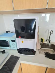eine Mikrowelle auf einer Küchentheke neben einer Spüle in der Unterkunft 2R2B Apartment 10 mins to KLCC in Kuala Lumpur