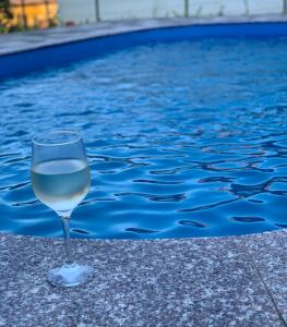 White Luxury Cottage- Mátrai Vadászház 4 في Mátraterenye: وجود كأس من النبيذ للجلوس بجوار حمام السباحة