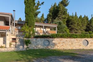 a house with a stone wall and a yard at Medusa Rooms in Kallithea Halkidikis