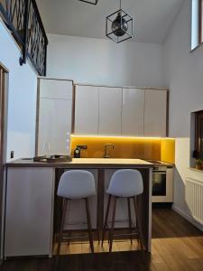 a kitchen with two white stools at a kitchen counter at Apartman Marin in Livno