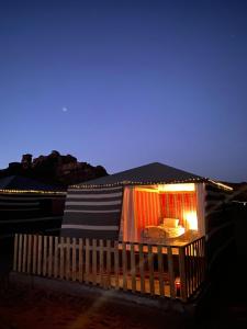 een klein gebouw met een bed in de nacht bij Desert's Soul Wadi Rum in Disah