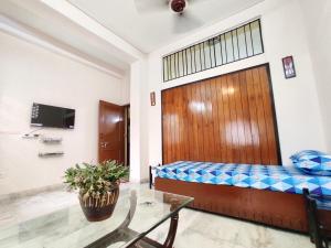 a room with a bed and a table and a tv at Spacious 3BHK House opp South City Mall in Kolkata