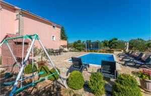 a backyard with a swing set and a pool at Four-Bedroom Holiday Home In Miranje in Miranje