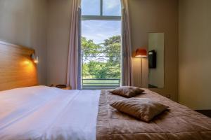 a bedroom with a large bed with a large window at Hôtel et SPA du Château in Lagord