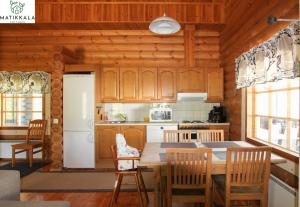 una cocina con armarios de madera, mesa y sillas en Matikkala Cottages, en Ruokolahti