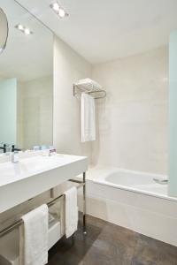 a white bathroom with a tub and a sink and a bath tubermott at VP Jardín de Recoletos in Madrid