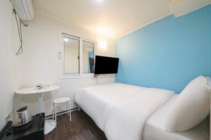 een slaapkamer met een wit bed en een kleine tafel bij J mini hotel & house in Seoul