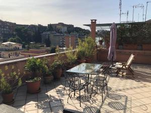 einen Balkon mit einem Tisch, Stühlen und einem Sonnenschirm in der Unterkunft Angelo Emo Terrace in Rom