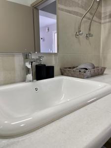 a white bath tub in a bathroom with a mirror at Arian Apartments in Argostoli