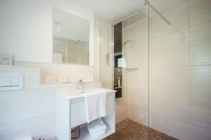 ein weißes Bad mit einem Waschbecken und einer Dusche in der Unterkunft Hotel Bären in Bernkastel-Kues