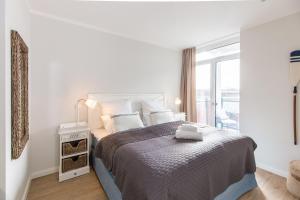 a white bedroom with a large bed with a window at Dockside Travemünde in Travemünde