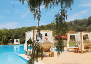 a swimming pool with two chairs and a swing next to a pool at Llucatx Menorca in Son Parc
