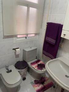 a bathroom with a toilet and a sink with purple towels at Mccoy avenida 3 in Macael