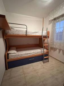 two bunk beds in a room with a window at Precioso piso con piscina a 10 min de la playa andando in Roquetas de Mar