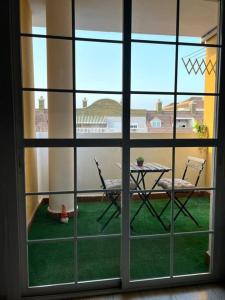 a view of a patio with a table and chairs through a window at Precioso piso con piscina a 10 min de la playa andando in Roquetas de Mar