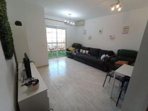 a living room with a couch and a tv at Precioso piso con piscina a 10 min de la playa andando in Roquetas de Mar