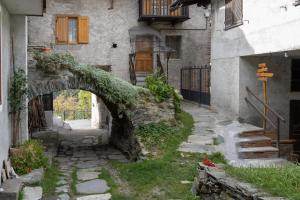 un antiguo edificio de piedra con un arco en un patio en Suite Bertines Panoramica - Borgata di montagna, en Casteldelfino