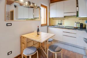 a kitchen with a wooden table and two stools at Allo Villo Lovely Apartment in Ostana