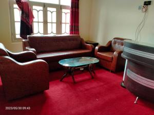 a living room with couches and a table and a piano at Stream View Guest House in Skardu