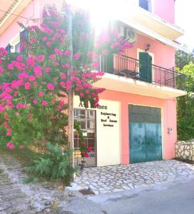 un edificio rosa con un árbol con flores rosas en Voukamvilia Boutique Apartment en Ágios Matthaíos