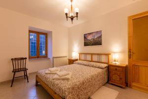 a bedroom with a bed and a chair and a window at Suite Bertines Panoramica - Borgata di montagna in Casteldelfino