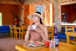 Paraguachi的住宿－Cala Margarita Hotel，坐在桌子边喝咖啡的戴帽子的女人