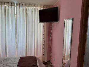 a bedroom with a television on a pink wall at CASA CAMPESTRE SANTERRA in Tacna