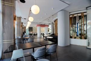 a restaurant with black tables and chairs and windows at Riviera Blue Hotel in Sunny Beach