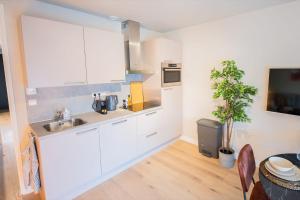 una cocina con armarios blancos y fregadero en Exquisite 3 Bedroom Apartment en Róterdam