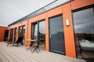 an orange building with a table and chairs on a deck at Exquisite 3 Bedroom Apartment in Rotterdam