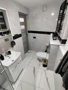 a white bathroom with a sink and a toilet at DEIZY Apartamenty in Wągrowiec