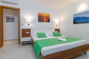 a bedroom with a large bed with green and white sheets at Villasanta De Luxe Apartments with Pool in Marusici 