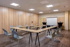 a conference room with tables and chairs and a whiteboard at Hôtel et SPA du Château in Lagord
