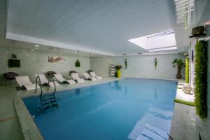 a large swimming pool with white chairs and a ceiling at Hôtel et SPA du Château in Lagord