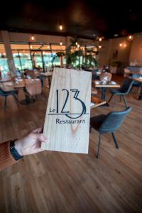 a person holding up a sign that reads restaurant at Hôtel et SPA du Château in Lagord