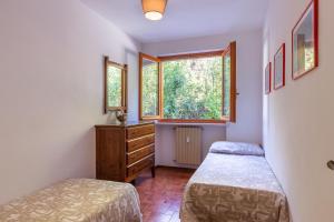 a bedroom with two beds and a dresser and a window at al Timo di Sampeyre in Sampeyre