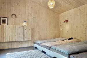 two beds in a room with wooden walls at Elf am See - Haus 7 in Templin