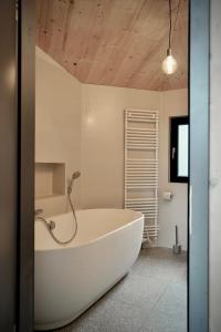 a white bath tub in a bathroom with a wooden ceiling at Elf am See - Haus 7 in Templin