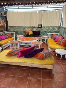 a room with couches and tables and colorful pillows at Riad 1001 couleurs in Marrakesh