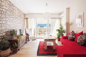 salon z czerwoną kanapą i ceglaną ścianą w obiekcie Evanthia's 2-SPACIOUS, CENTRAL, 2BDR APART,+BALCONY w Atenach