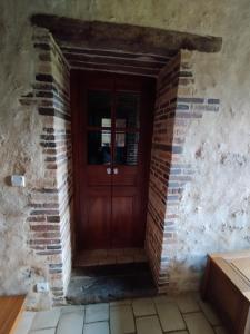 a brick wall with a wooden door in a room at Chambre d'Hôtes La Ferme du Pré-Martin in La Génevraie