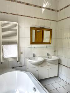 uma casa de banho com 2 lavatórios, uma banheira e um espelho. em Au Bel Étage em Saarbrücken