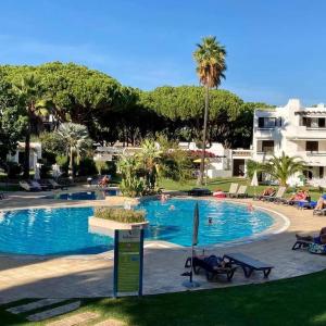 a large swimming pool with palm trees and a building at Albufeira - Casa Balaia Resort in Albufeira