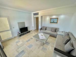 a living room with a couch and a television at Beachfront Apartment - Andalucia in Bizerte